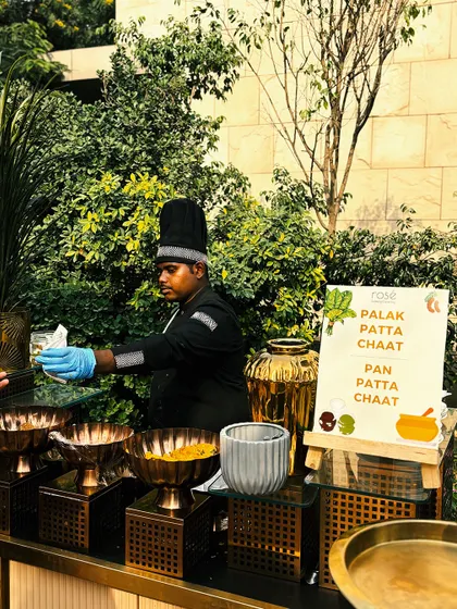 A chef at our live Palak Patta Chaat counter prepares a crispy, tangy snack for a guest. This outdoor setup is perfect for daytime events, bringing the vibrant flavors of Delhi street food to a sophisticated setting.