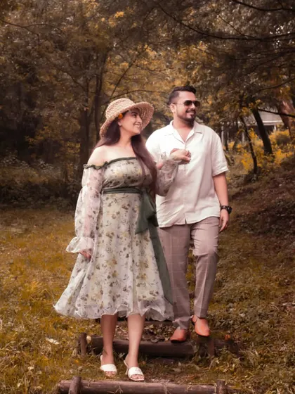 A candid moment of the couple, showing how their outfits work together in the woodland setting. His simple white shirt and trousers complement her floral dress, creating a cohesive and relaxed look.