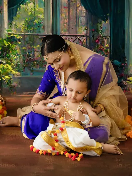 A tender moment as a mother adjusts her son's pearl necklace during their Krishna-themed shoot.