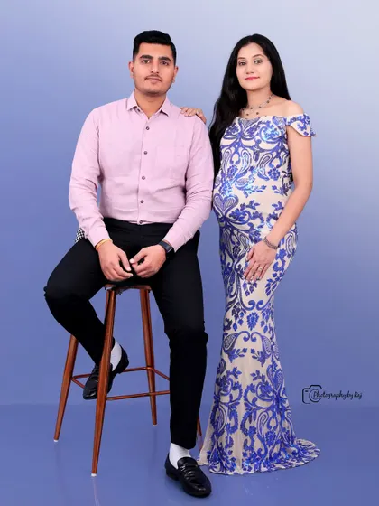 A classic studio portrait of a couple, with the mother-to-be in a blue and white sequined gown.