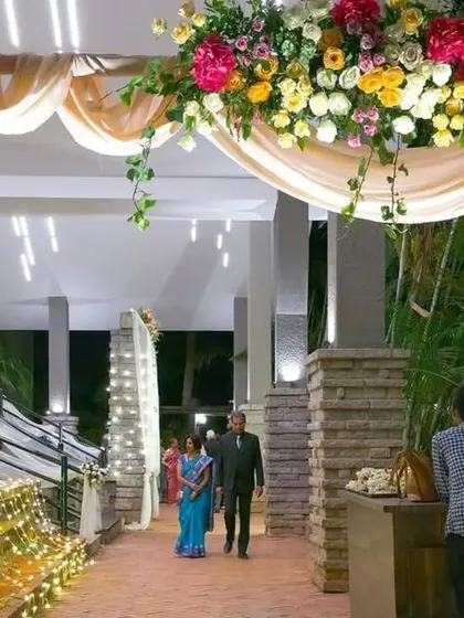 A lush and beautiful floral archway for a wedding entrance. The combination of colorful flowers, green foliage, and soft lighting creates a stunning welcome for your guests.
