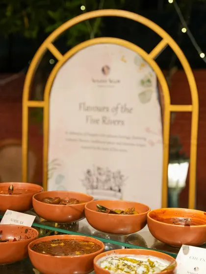 Our "Flavours of the Five Rivers" station, showcasing a variety of traditional Punjabi dishes and pickles in rustic earthenware bowls. This concept celebrates the rich culinary heritage of the region.