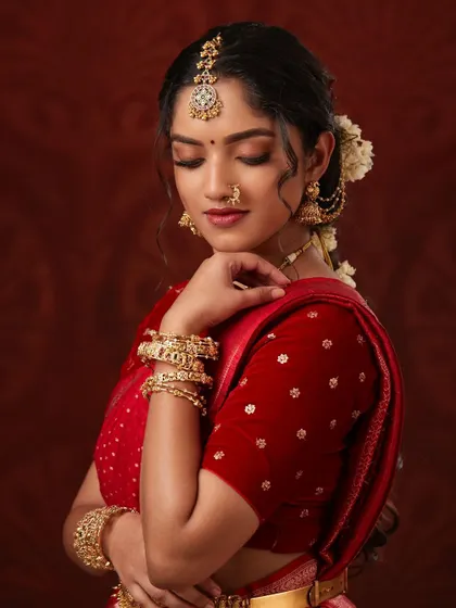 A beautiful model in a red saree, adorned with a stunning antique choker, maang tikka, and nose ring.