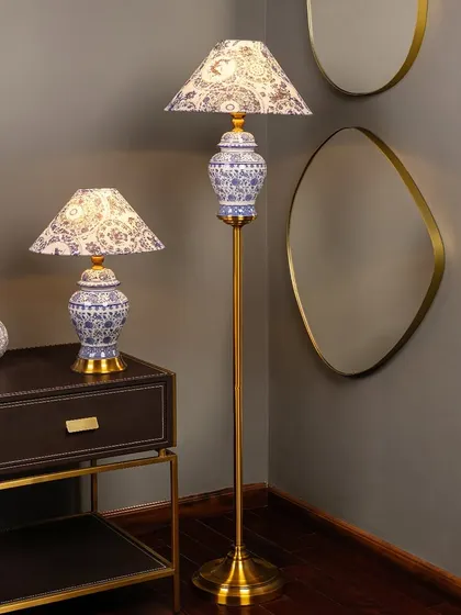 Here you can see the table and floor lamp combo in a room setting. The matching blue pottery bases and patterned shades create a cohesive and sophisticated look, perfect for a living room or bedroom corner.