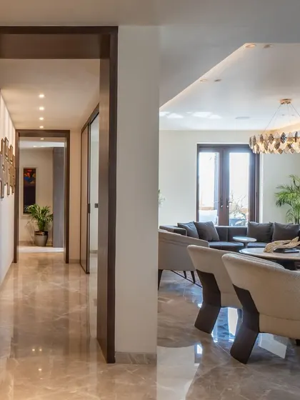 A view showing the flow from the hallway into the main living area of this Gurugram residence. The consistent use of materials and color palette creates a sense of cohesiveness throughout the home.