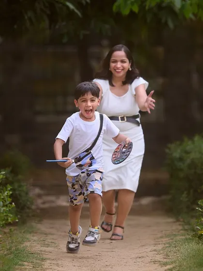 A playful chase during a family photoshoot. This action shot captures the fun and energy of childhood, with mom joyfully following close behind.
