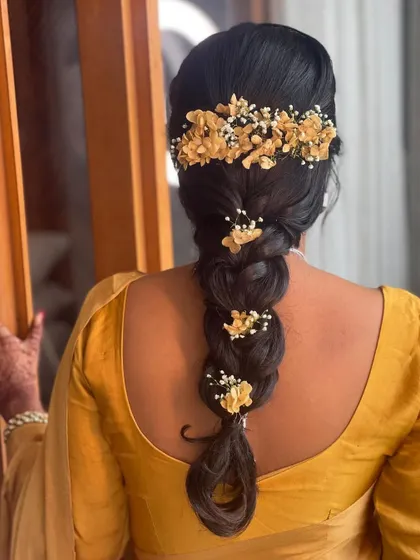 For this Haldi look, I created a simple, loose braid and adorned it with beautiful yellow flowers and baby's breath to match the bride's saree.