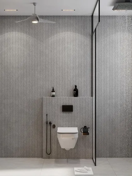 A minimalist bathroom design featuring clean lines and a serene atmosphere. The wall-mounted toilet and sleek glass shower partition are set against a backdrop of subtle gray chevron tiles, creating a spacious and calming feel.
