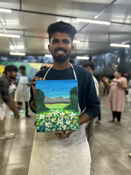A proud artist holding up his beautiful landscape painting. Every participant gets to take their artwork home as a reminder of a fun, creative day with their team.