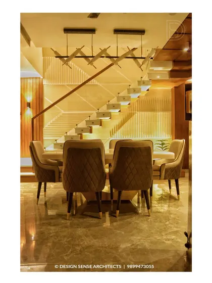 This dining area is defined by the stunning modern staircase behind it. The design uses clean lines, integrated lighting, and plush quilted chairs to create a sophisticated space for family meals.
