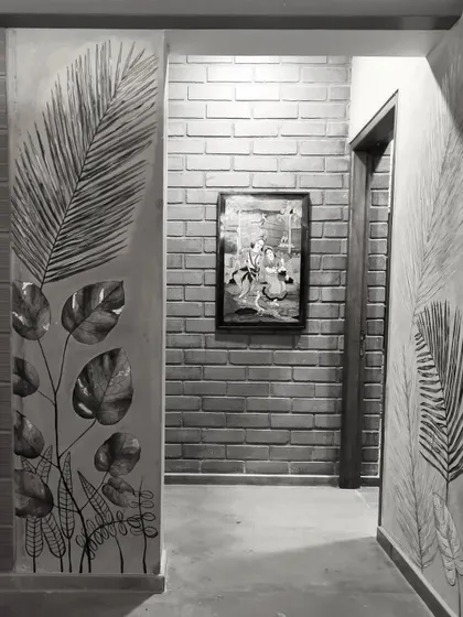 The same corridor in black and white, emphasizing the textures and patterns of the wall art and brickwork.