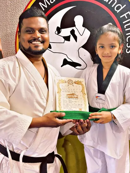 This young practitioner proudly accepts her new green belt, a symbol of her growing skill and dedication to Taekwondo.