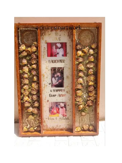 A straight-on shot of the large format varmala frame, showcasing the "Love, Laughter & Happily Ever After" text, multiple photos, and the beautifully preserved garlands.