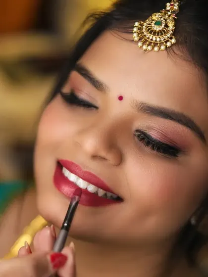 A close-up of the makeup artist applying lipstick, one of the final touches to the bride's look.
