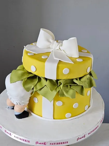 A full shot of the yellow polka dot gift box cake, highlighting the large, handcrafted fondant bow on top.