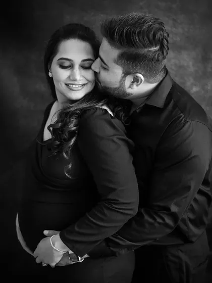 A classic and romantic black and white portrait of the expecting couple. The gentle kiss and embrace create a timeless image filled with love and tenderness.