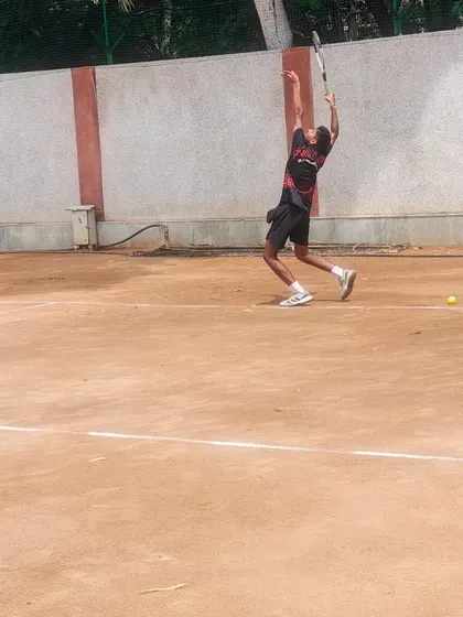 Capturing the peak of the service motion. This player is demonstrating the full body extension required for a powerful and effective serve, a key focus in our training.