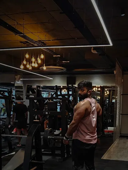 The gym is my studio. This pose captures the size and definition of my back and shoulders under the gym's ambient lighting.