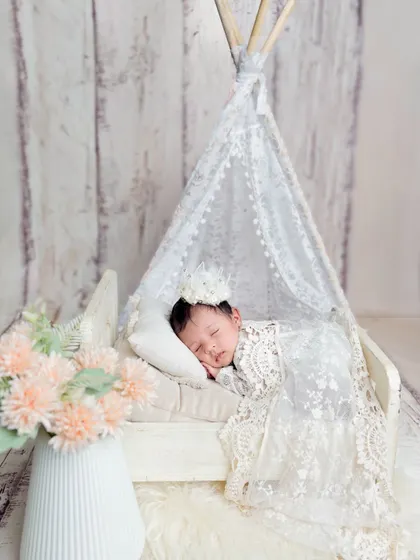 A little princess in her miniature teepee. This dreamy setup with a lace canopy and a tiny bed creates a whimsical and magical portrait.