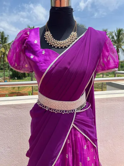 A purple half saree with puff sleeves and a silver border, styled with a belt.