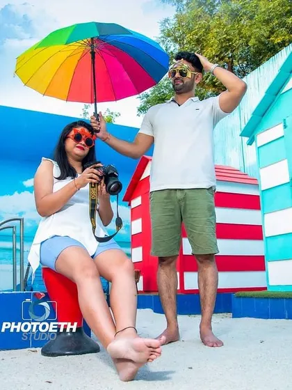 A colorful and fun poolside shot with a rainbow umbrella. This beach-themed setup is great for couples who want a vibrant and playful pre-wedding album.