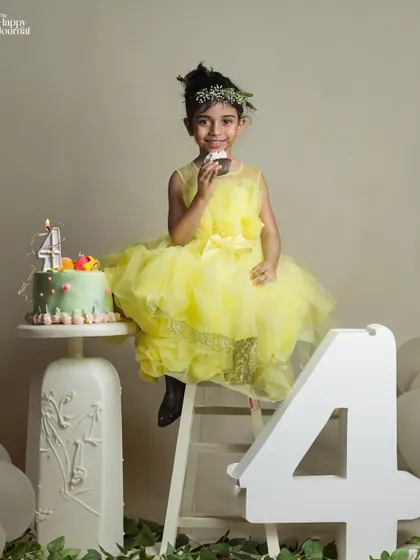 Happy fourth birthday! A girl in a bright yellow dress sits next to her birthday cake, celebrating her special day in style.