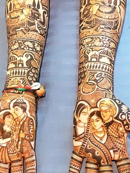 This bridal mehendi is a true work of art, featuring multiple custom portraits. On one hand, a portrait of the couple, and on the other, a beautiful depiction of the bride with her family.