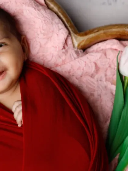 A smile that could launch a thousand ships. This baby's joyful expression is the centerpiece of this vibrant, red-themed floral shoot.