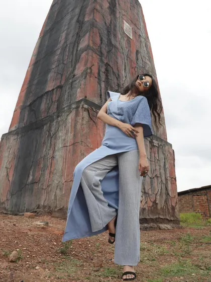 A designer shoot against a rustic, architectural backdrop. I styled this blue jumpsuit with a unique silhouette to create a strong contrast with the textured, earthy tones of the location.