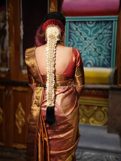 A bridal hairstyle is a crown. Here, you can see the detail of a traditional South Indian jada, intricately woven and adorned with fresh jasmine flowers and classic hair jewels.