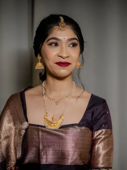 A close-up portrait of the bride. Her makeup features a classic winged eyeliner and a deep red lip, a timeless combination for any bride.