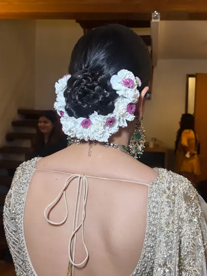 Another perspective of the detailed floral bun. The placement of small pearls within the woven hair adds a subtle touch of glamour, a finishing detail we focus on in class.