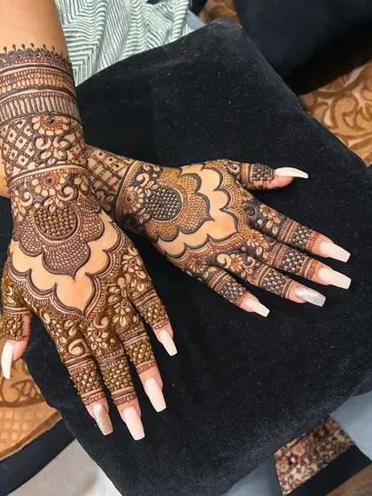 Picture perfect. This design features a classic mandala on the back of the hand with intricate wrist and finger details, beautifully complementing the client's long nails.