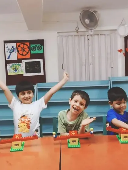 The joy of creation is evident on these boys' faces as they display their finished seesaw models. They have successfully applied principles of balance and mechanics.