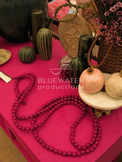 A tabletop vignette showing the eclectic mix of props used for the Gond art-themed lunch, including beaded necklaces and ceramic pomegranates.