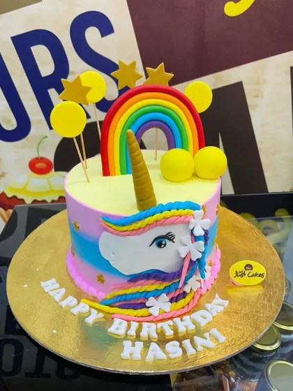 A vibrant 2.5kg unicorn cake with a rainbow-colored mane and a golden horn.