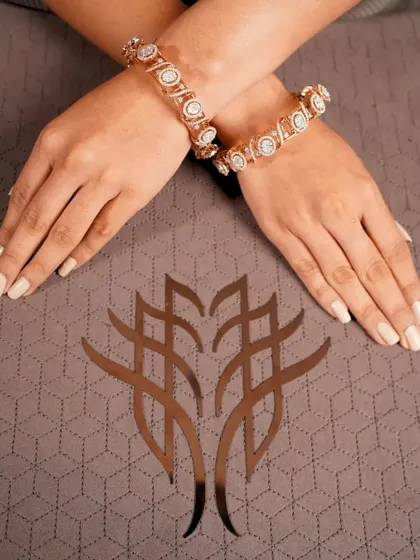 A pair of substantial diamond kadas, or bangles, crossed over a branded cloth. This image highlights the beauty and impressive craftsmanship of these traditional yet timeless pieces.