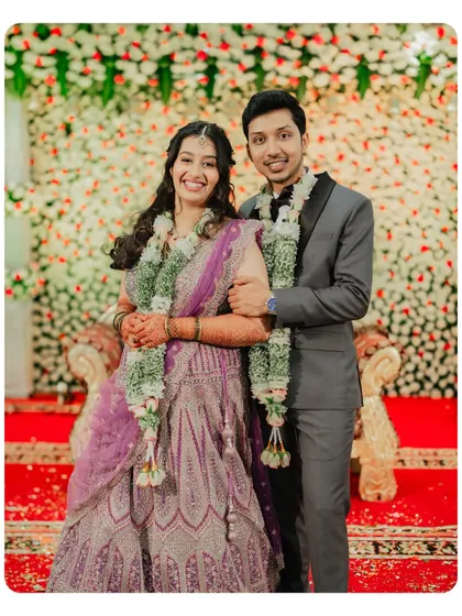 The couple poses for a classic reception photo, their elegant attire complementing the beautiful floral decor.