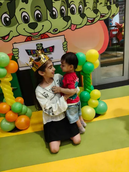 A sweet moment between siblings at a birthday party. The birthday girl, wearing her crown, shares a hug with her younger brother.
