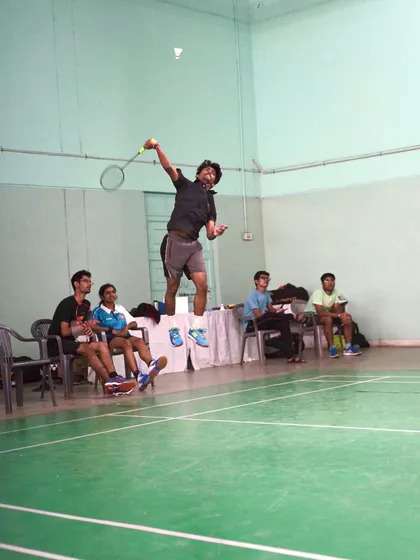 A player mid-air, demonstrating the form and technique required for a powerful overhead shot during a match.