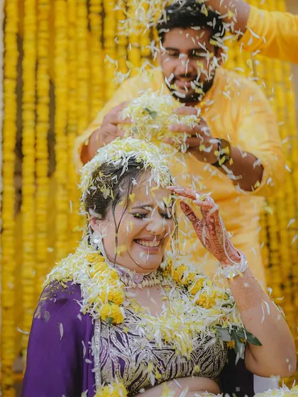 The bride's joyous reaction as she is showered with flowers during her Haldi ceremony, a moment of pure, unadulterated happiness.