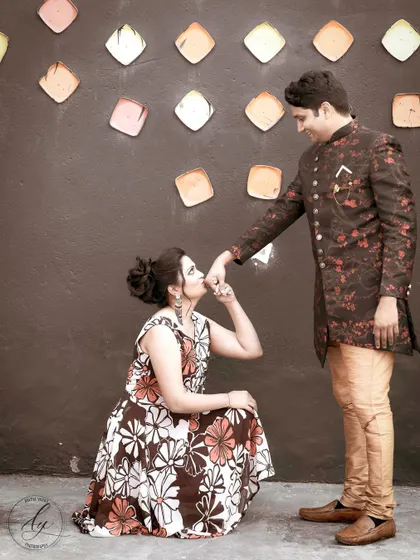 A classic romantic pose during a pre-wedding session. The bride-to-be kneels and kisses her partner's hand, creating a charming and traditional portrait that celebrates their commitment.