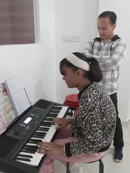 An instructor observing his student's keyboard practice, ensuring she develops the correct posture and technique.