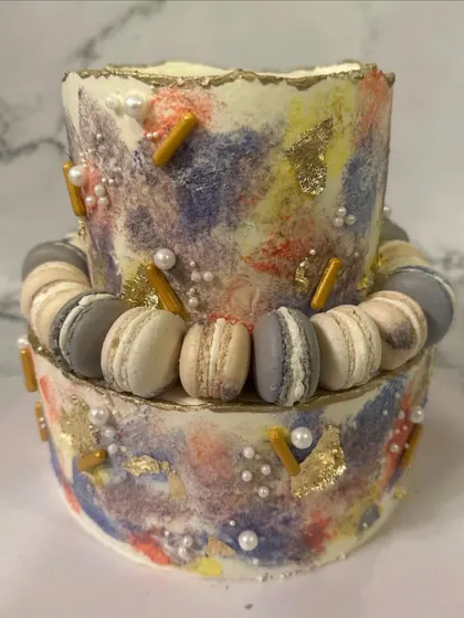 A playful and modern two-tier birthday cake. The colorful palette knife texture is accented with a ring of assorted macarons, adding a fun and delicious twist to the design.