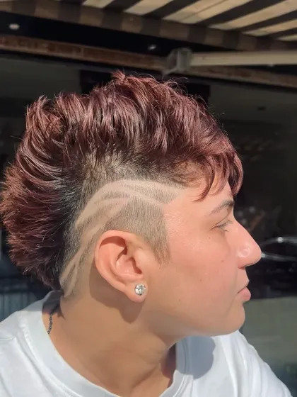 Hair is a canvas for art. This edgy mohawk style is combined with a custom hair tattoo, a design shaved into the side for a truly unique and bold statement. This is for clients who want to push boundaries and wear their personality.