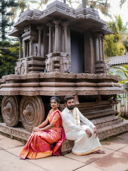 A relaxed portrait of a couple sitting by our Hampi stone chariot replica.