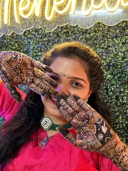 The bride showing off her intricate mehendi design. The green backdrop with the neon sign makes for a very trendy photo.