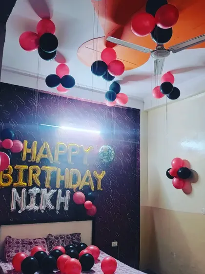 A wider view of the red and black birthday decor, showing how the balloon clusters are arranged across the ceiling to fill the space.