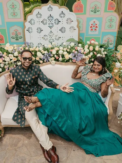 The couple strikes a fun pose, showing off their Mehendi-adorned hands and feet.