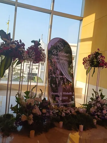 An elegant welcome setup inside a hotel lobby, with a custom sign and sophisticated floral arrangements.